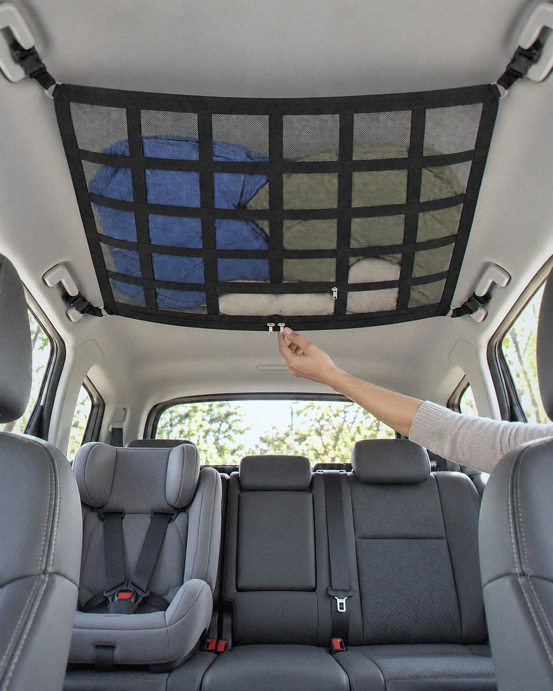 Parent reaching up to unzip an overhead cargo net above a child seat